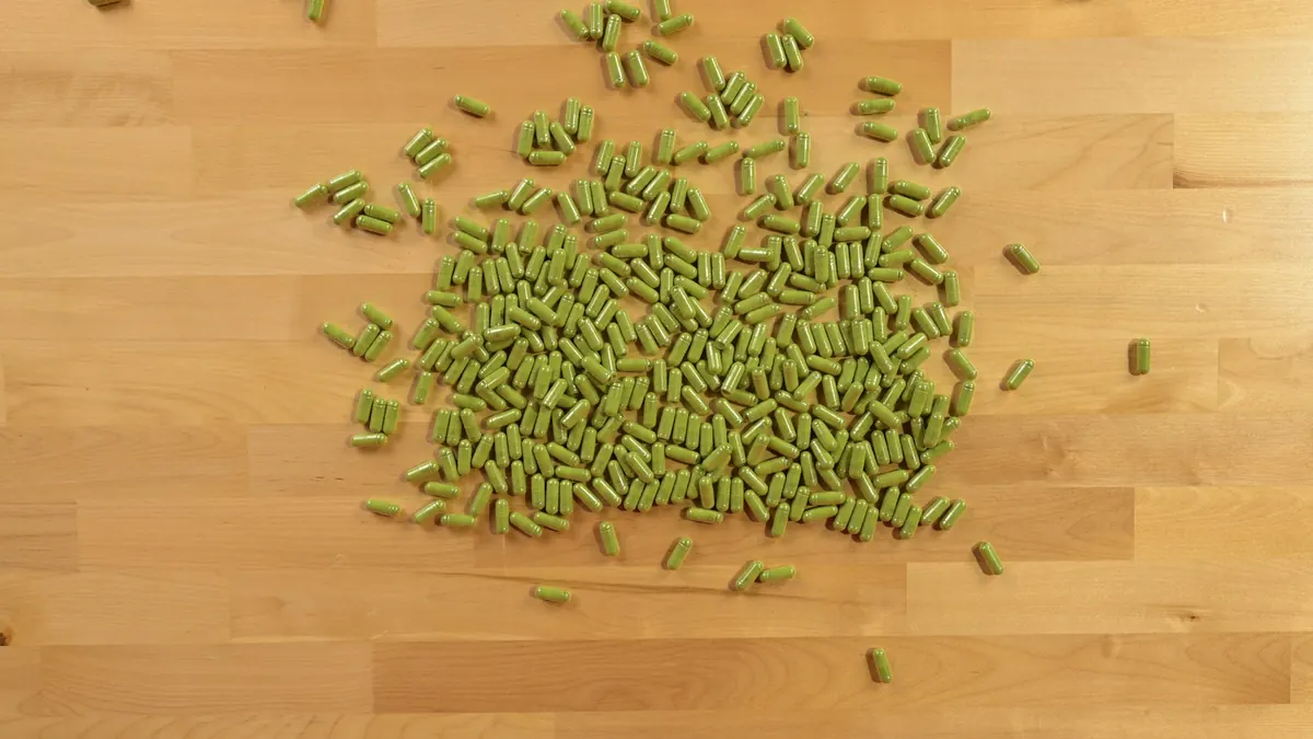 Groene capsules op een houten ondergrond